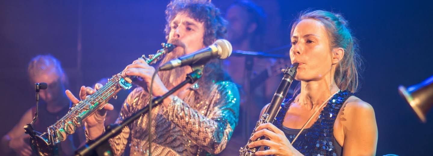 Del av en musikensemble: en man och en kvinna som spelar blåsinstrument.