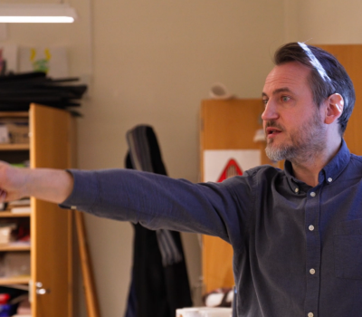 Manlig lärare pekar med en penna i ett klassrum.