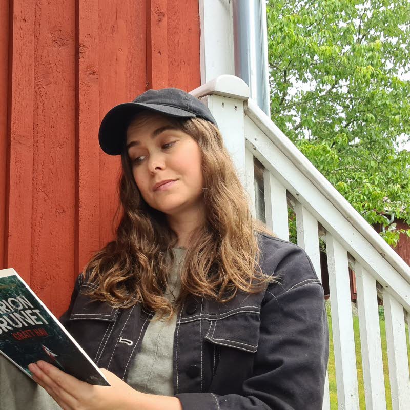 Läsambassadören läser en bok på en trappa.