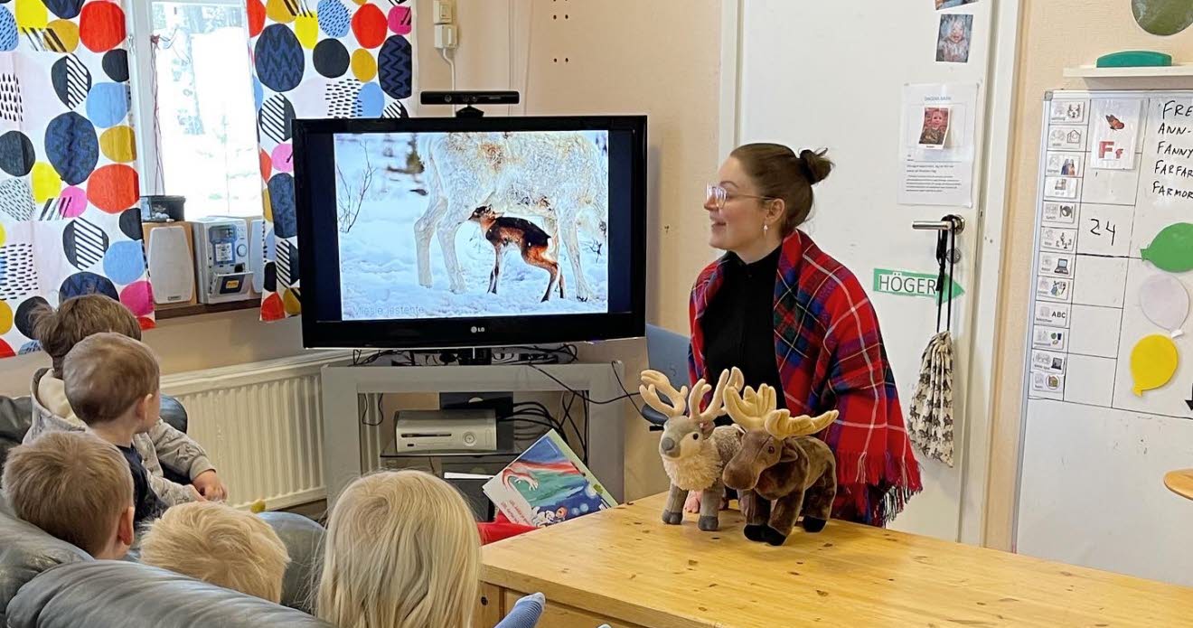 Berättarstund med små barn som tittar på bild på renar.