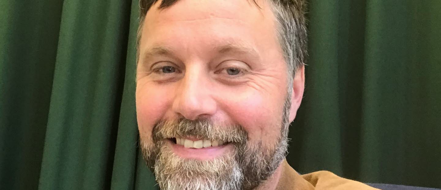 Bild på John Bjerkert, med grön bakgrund.