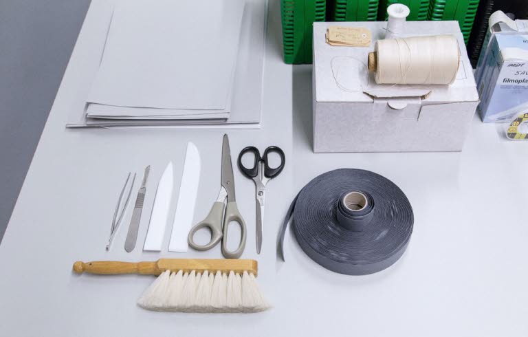 Bord med olika föremål som sax, tejp, borste, anteckningsblock.