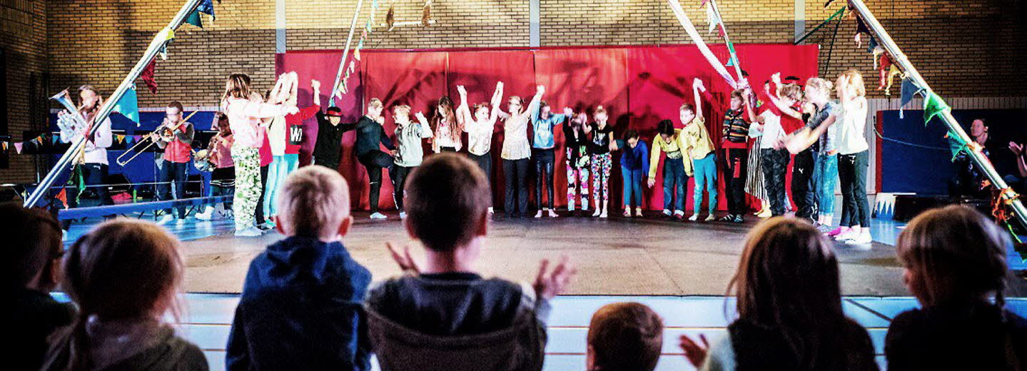 Barn uppträder med cirkus på en scen
