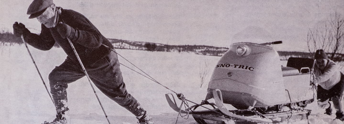 Man på arkivfoto på skidor som drar en skoter. 