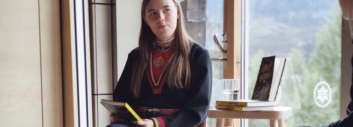 Kvinna samtalar vid fönster.