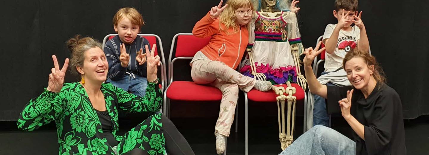 Två pedagoger och tre barn poserar med ett pyntat skelett.