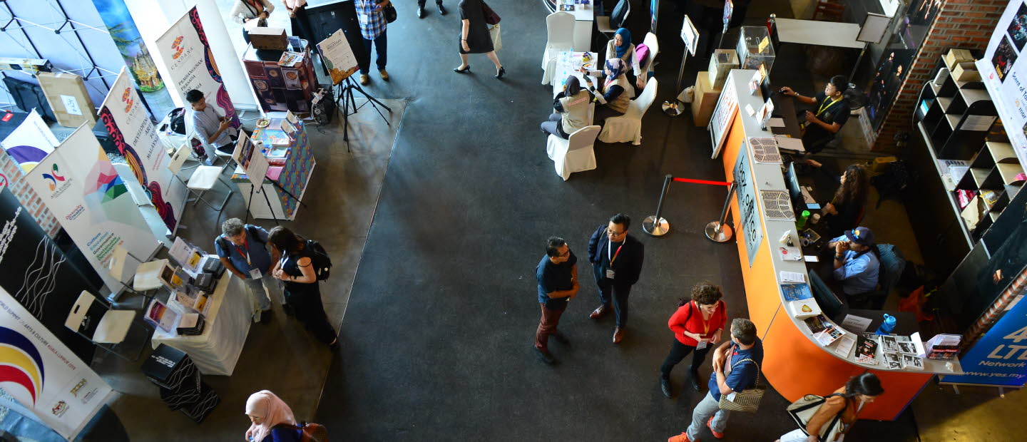 Foto taget ovanifrån på ett golv fyllt av människor och informationsbord.