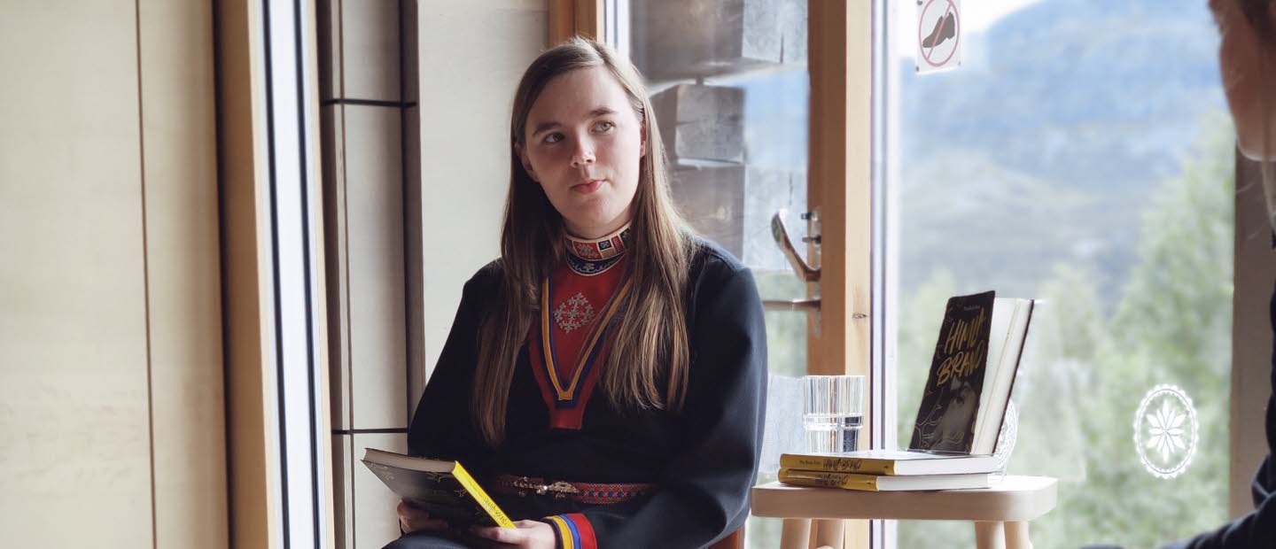 Kvinna samtalar vid fönster.