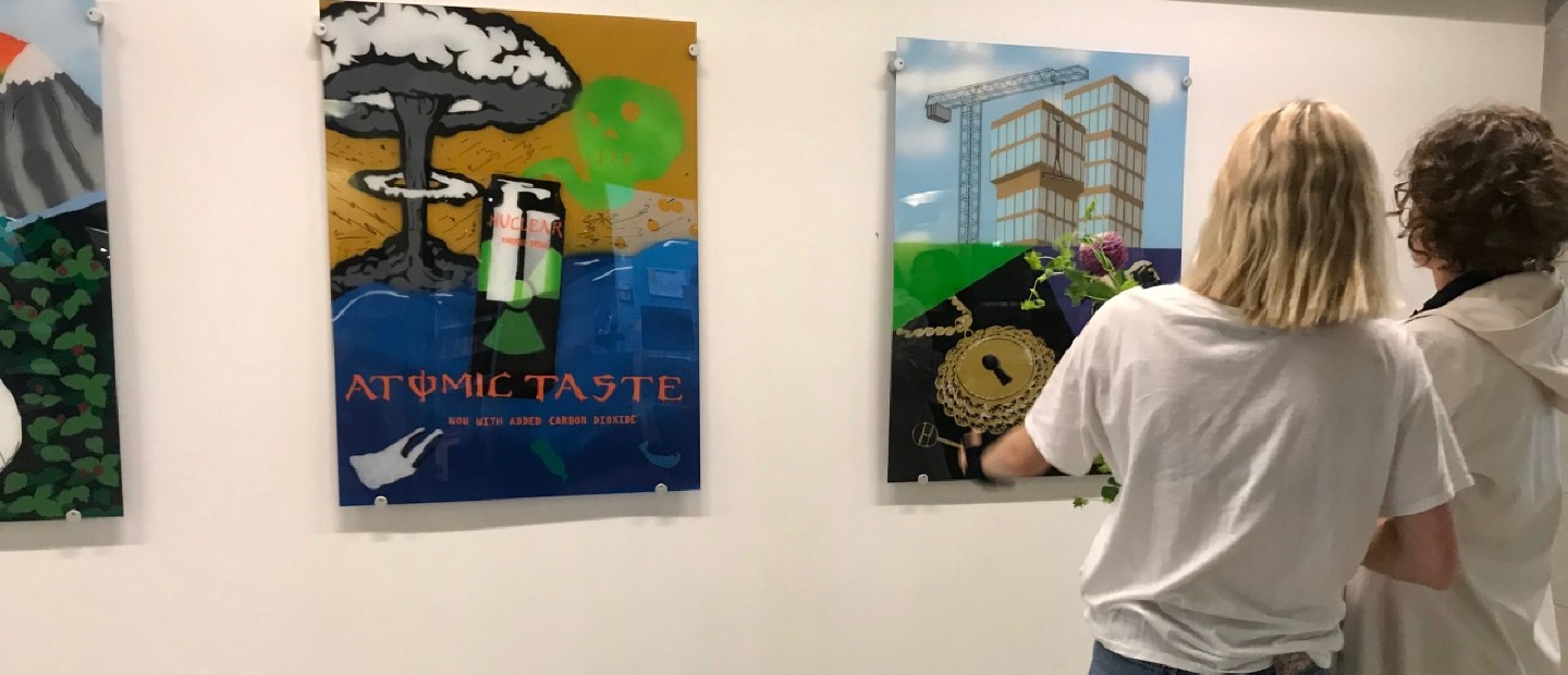 Två personer ser på tavlor som hänger på en vägg. 