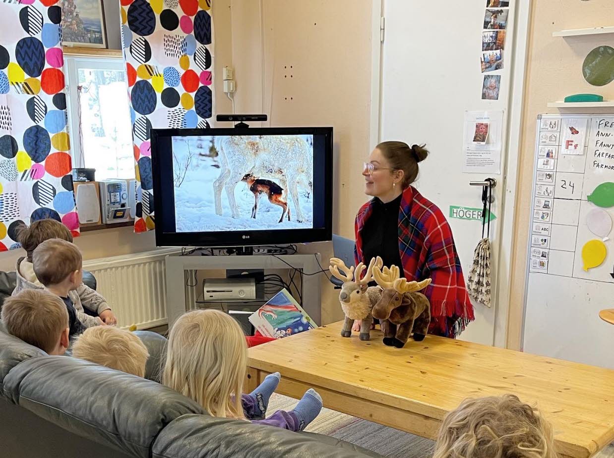 Berättarstund med små barn som tittar på bild på renar.