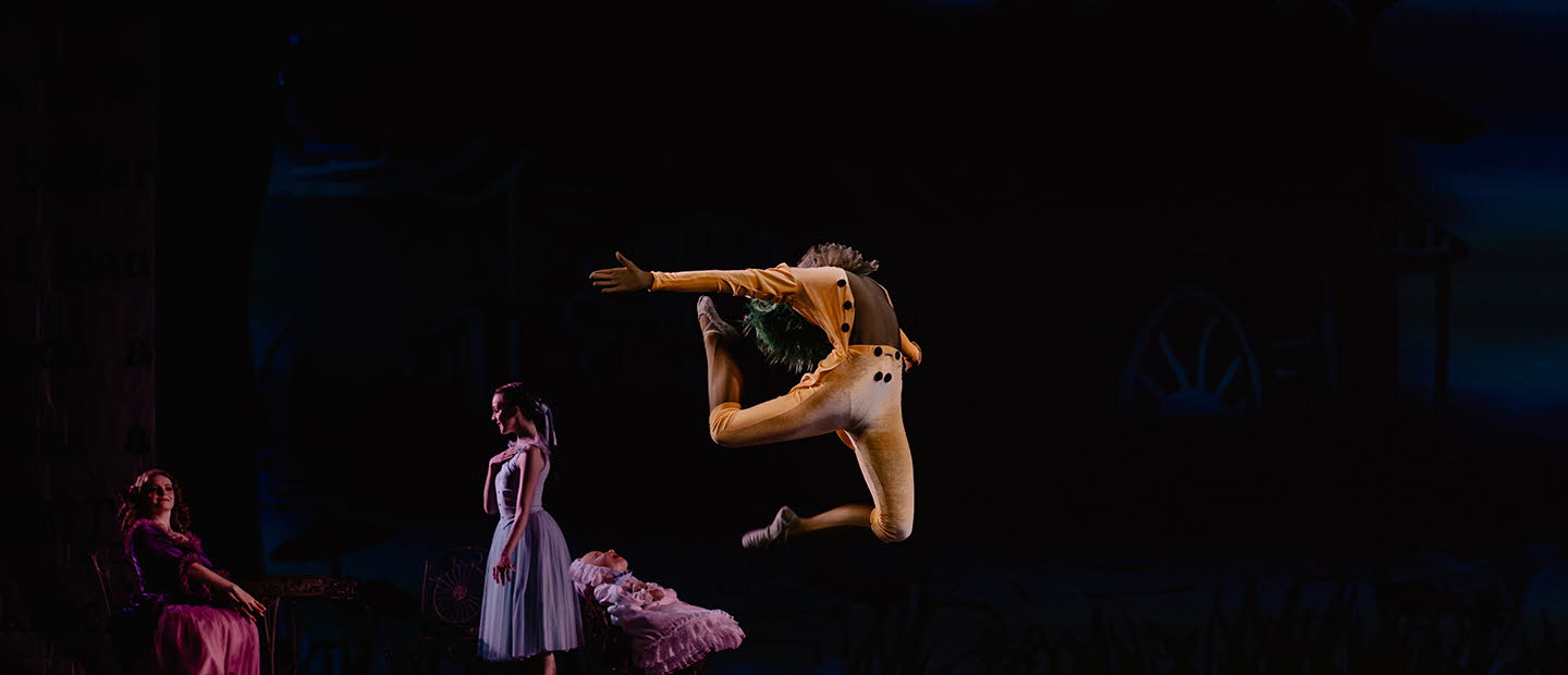 Uppträdande på scen med dansare. En man i orangea kläder kastar sig upp i luften.