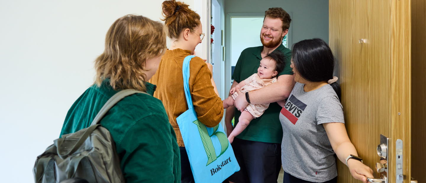 Två medarbetare som arbetar med Bokstart gör ett hembesök. Möter en familj i trapphuset.