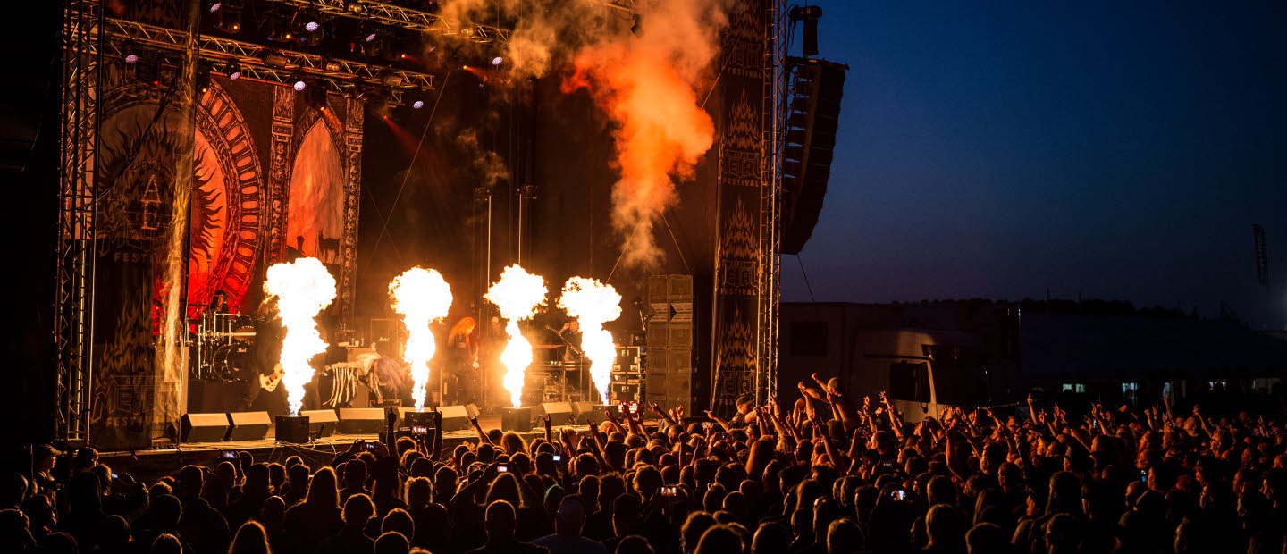 An outdoor music concert with fireworks on stage.