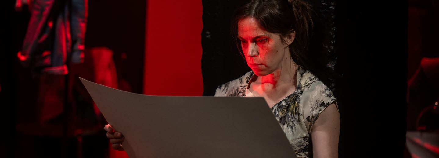 Läsande sittande kvinna belyst av rött ljus.