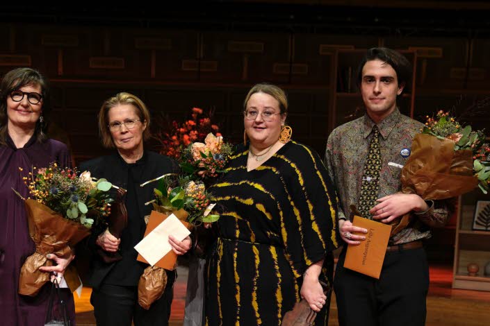 The four laureates stands together with flowers in their hands.