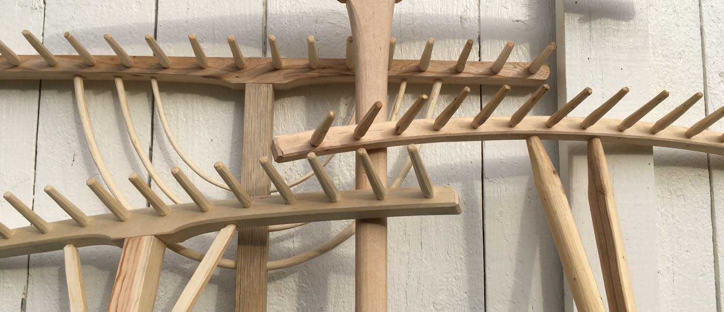 Fyra handtillverkade träräfsor mot en vägg.