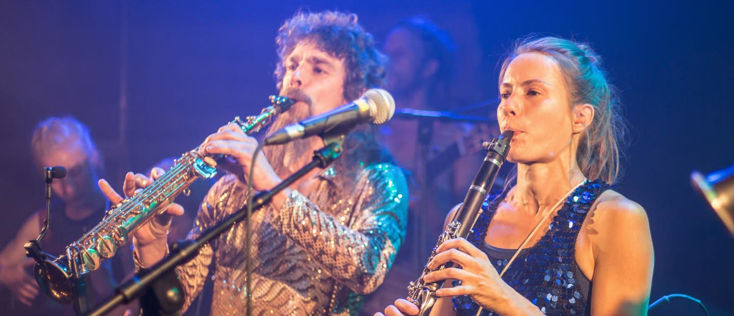 Del av en musikensemble: en man och en kvinna som spelar blåsinstrument.