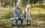 ALMA laureate Eva Lindström and her dog sitting at a bench in the wood.
