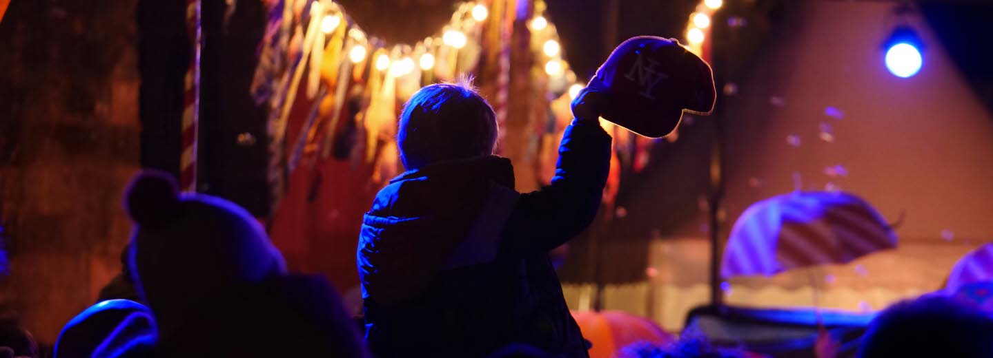 Publik framför en scen i dunkel lila beslysning.